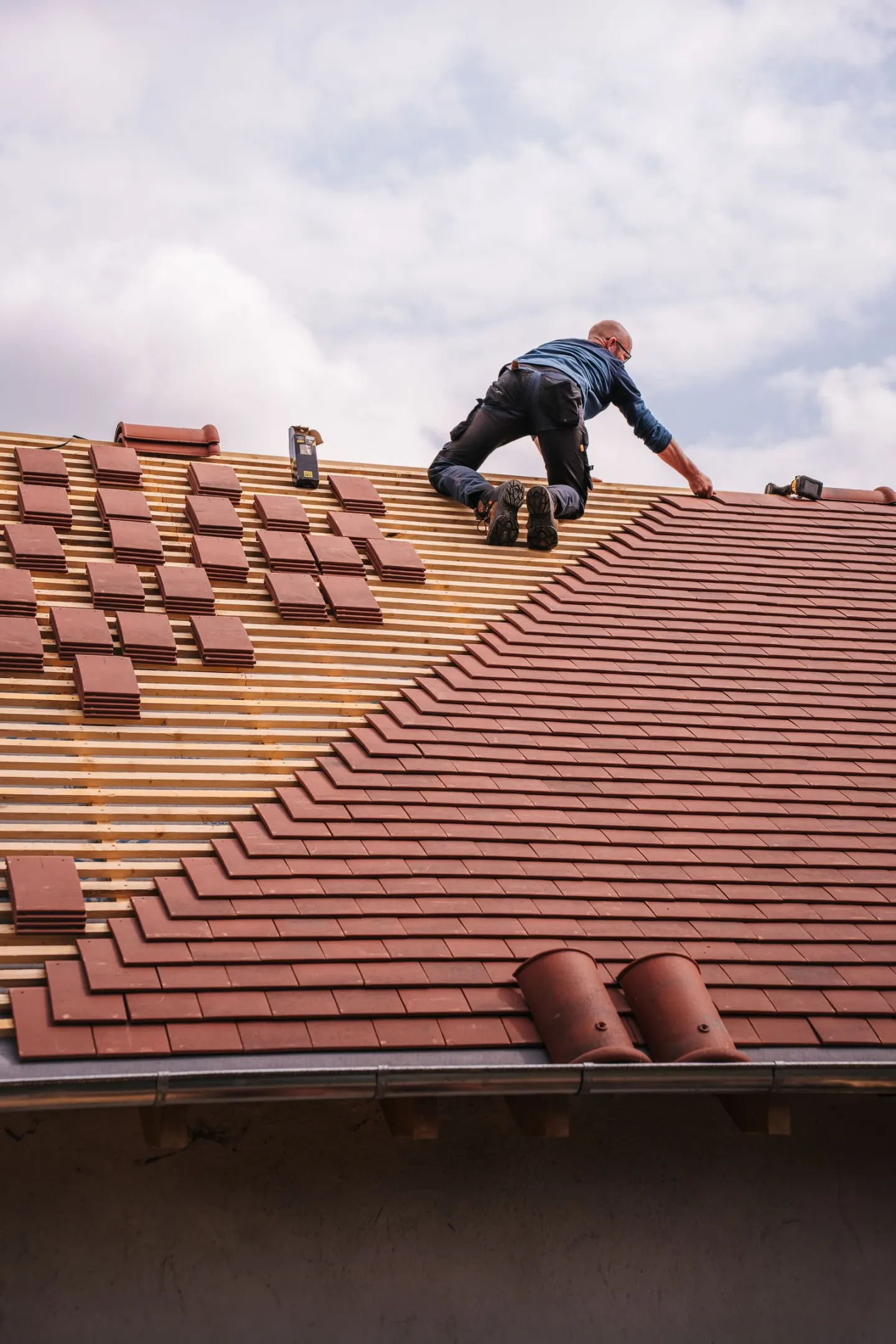 A roofer aligning asphalt shingles over underlayment on a residential roof